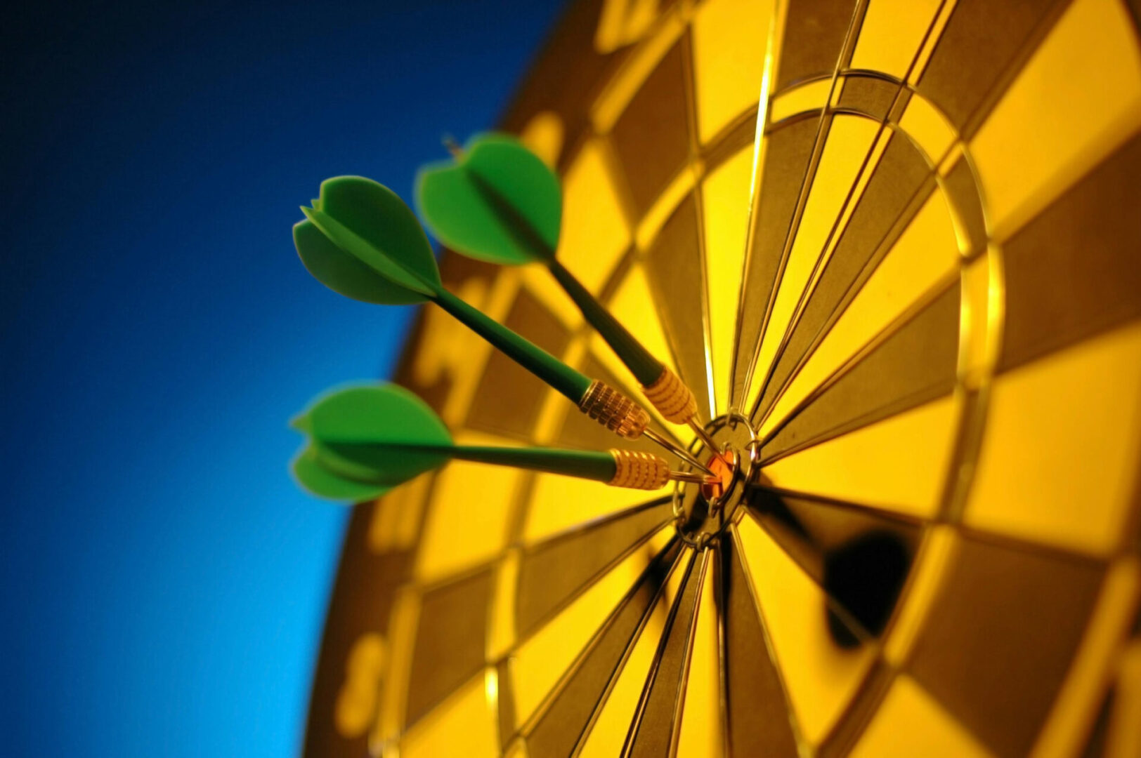 Three green darts in the center of a yellow target.