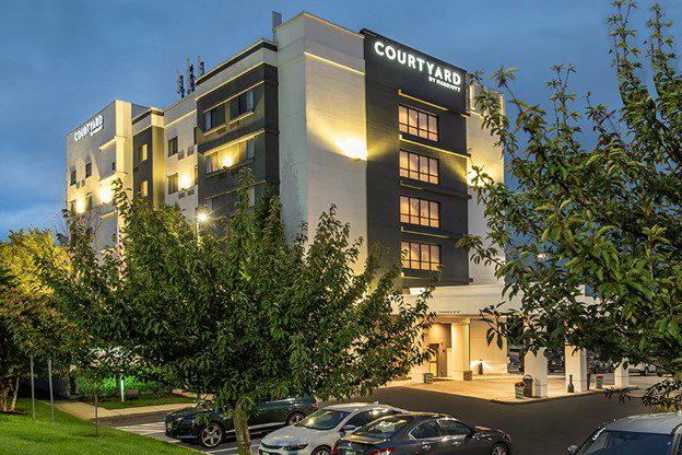 A large hotel with cars parked in front of it.