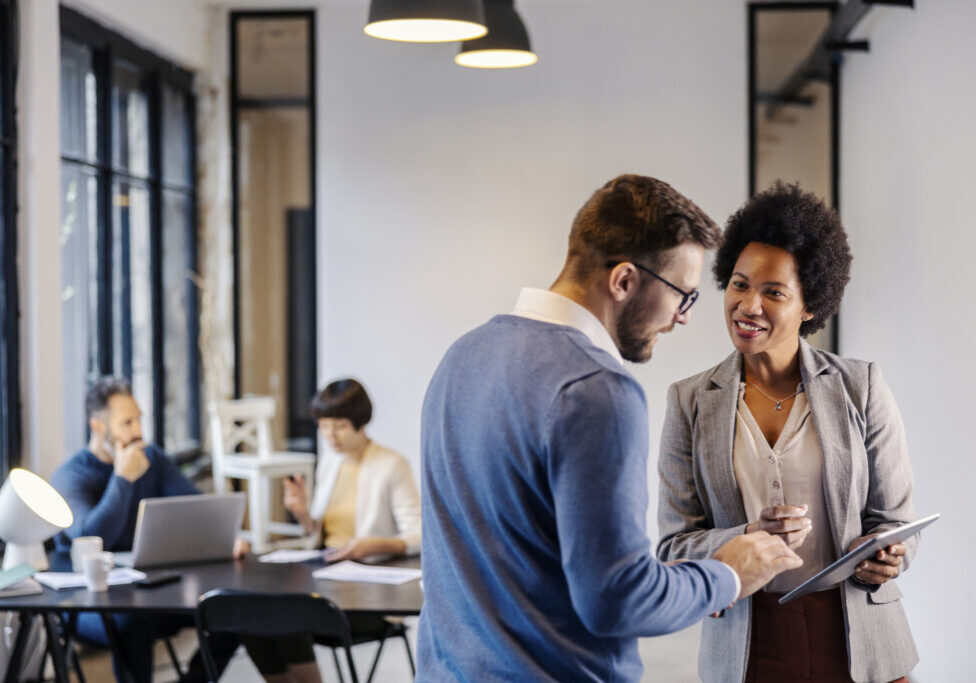 Two colleagues discussing work in an office.